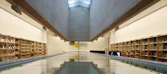 Interior de la biblioteca del MARCO con estanterías de madera y techo inclinado