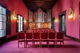 Sala de eventos con órgano y butacas rojas