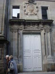 Fachada principal del Edificio Sarmiento con puerta blanca y escudo heráldico