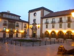 Plaza de Feijoo iluminada al atardecer con arcos y edificios coloniales en Oviedo