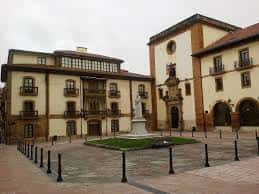 Plaza de Feijoo en Oviedo con fachadas históricas y estatua central bajo cielo nublado