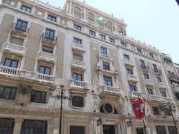 Vista frontal del edificio del Santander en Sevilla con bandera española y detalles arquitectónicos destacados