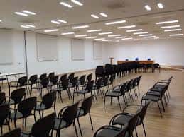 Sala de conferencias preparada con sillas y mesas para eventos corporativos