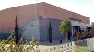 Vista exterior del edificio del Centro Deportivo Pino Montano con fachada de ladrillo y vegetación