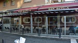 Fachada exterior del Bar Batela con toldo rojo y mesas en la acera