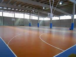 Pista de pádel interior con suelo naranja y columnas azules