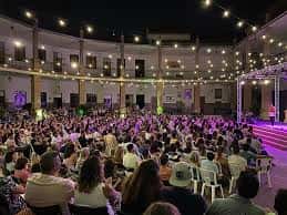 Patio lleno de gente bajo luces de fiesta, ambiente festivo en El Patio de Triana