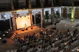 Escenario con proyección y público en el patio, vista desde arriba durante un evento