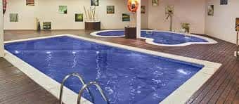 Vista amplia de la piscina interior del spa con escalera de acceso y suelo de madera