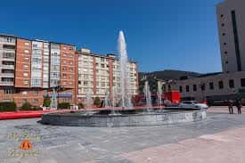 Fuente central en la Plaza de los Ferroviarios con chorros de agua y edificios residenciales al fondo