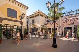 Vista exterior del McArthurGlen Designer Outlet Málaga con arquitectura mediterránea y peatones caminando