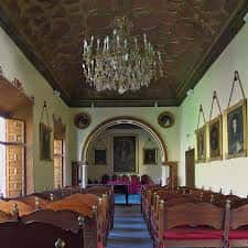 Sala de actos con techo decorado y candelabro