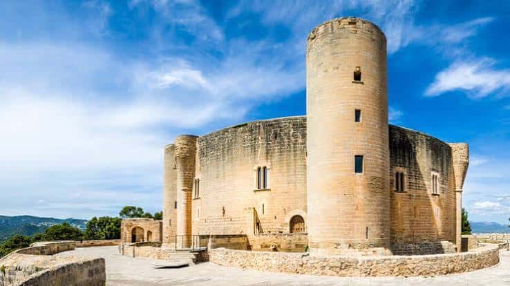 Fachada lateral del castillo con torres cilíndricas bajo cielo despejado