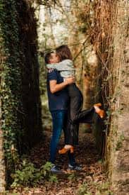 Momento romántico de pareja entre árboles cubiertos de hiedra en el bosque