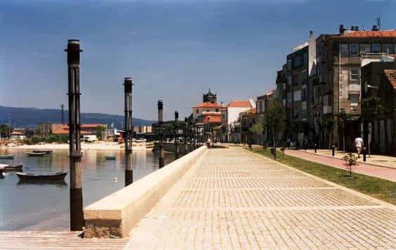Paseo marítimo de Bouzas con edificios costeros y embarcaciones al atardecer
