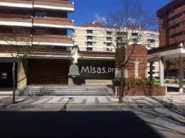 Plaza frontal de la parroquia con estatua de Cristo y campana, bajo cielo despejado