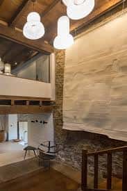 Área de la galería con iluminación moderna y una pared de piedra con una obra texturizada