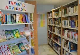 Sección infantil de la biblioteca con estantería de novedades y libros coloridos