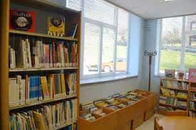 Área de lectura junto a ventana con estanterías bajas y libros expuestos