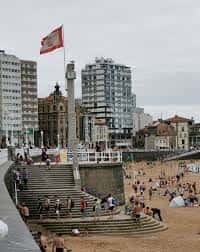 Vista panorámica de La Escalerona con la bandera de Gijón ondeando y la playa de San Lorenzo al fondo