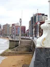 Detalle de la escalera monumental con escultura blanca y vista del paseo marítimo