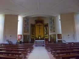 Interior de la iglesia con bancos de madera y altar principal