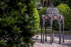 Pabellón ornamental de hierro forjado entre setos verdes