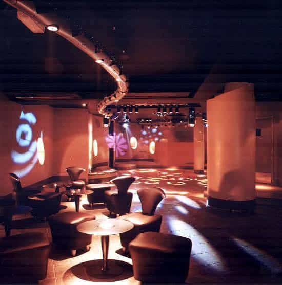Sala de estar del Club Revenge con mobiliario moderno y luces decorativas