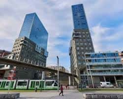 Torres Isozaki en contexto urbano con tranvía y peatones