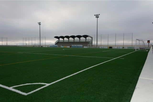 Vista general del campo de fútbol con césped artificial y gradas cubiertas
