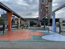 Pista polideportiva de Laviada con zonas de juego coloreadas y estructura urbana al fondo