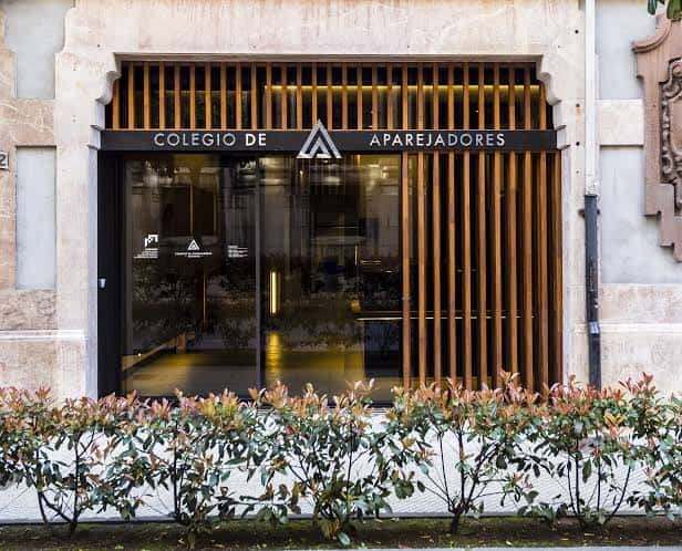 Fachada moderna del Colegio de Aparejadores con detalles arquitectónicos y vegetación