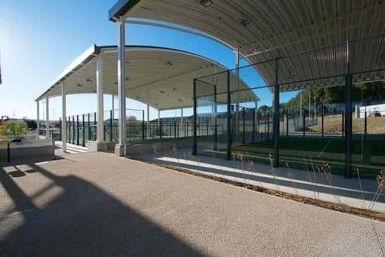 Pista de pádel cubierta con estructura metálica y suelo de tierra batida