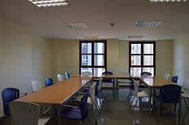 Sala de reuniones con mesas largas y sillas azules