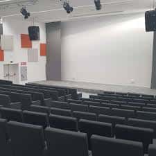 Escenario amplio con pantalla blanca y asientos dispuestos para conferencias