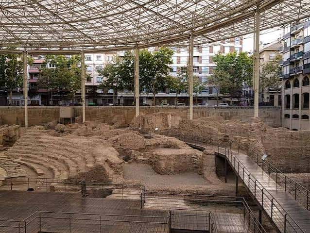 Vista de las ruinas arqueológicas bajo una estructura de techo metálico en la plaza