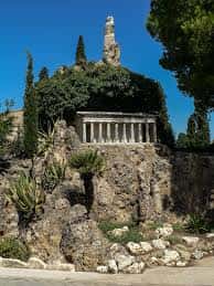 Monumento funerario con estatua y estructura clásica rodeado de vegetación