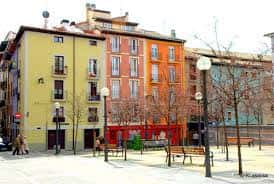 Plaza de la Compañía en Pamplona con bancos, árboles y edificios históricos al fondo