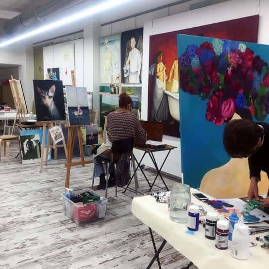 Interior del espacio mostrando un taller de pintura en actividad con artistas trabajando
