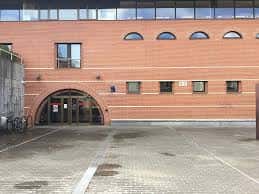 Entrada principal del edificio con arco de ladrillo y plaza frontal en un día despejado