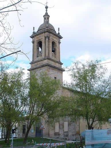 Plano cercano de la torre de la iglesia con detalles arquitectónicos y campanas visibles