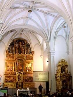 Interior de la iglesia mostrando el retablo mayor dorado y bóvedas de crucería