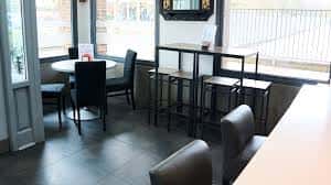 Zona de estar con mesas altas y sillones junto a ventana