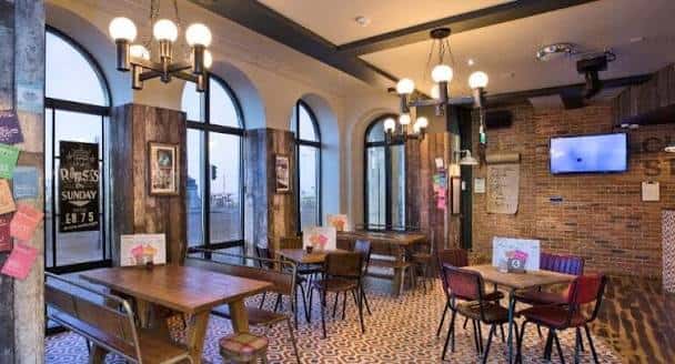 Interior del Charles Street Tap con mesas de madera y ventanas arqueadas