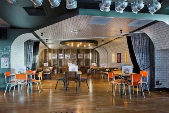 Sala principal del Charles Street Tap con iluminación moderna y sillas naranjas