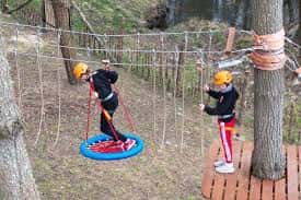 Niños participando en una actividad de cuerdas con casco y arnés