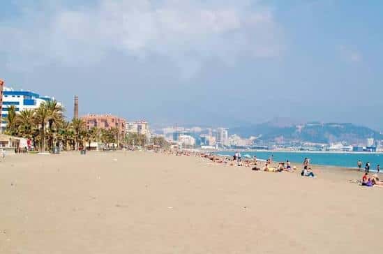 Playa de la Misericordia con palmeras y visitantes disfrutando del sol y el mar
