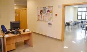Interior del centro social mostrando zona de recepción y sala de reuniones con mesas y sillas