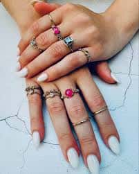 Manos luciendo anillos de diseño artesanal sobre superficie clara