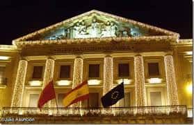 Vista nocturna del Palacio de Navarra iluminado con banderas